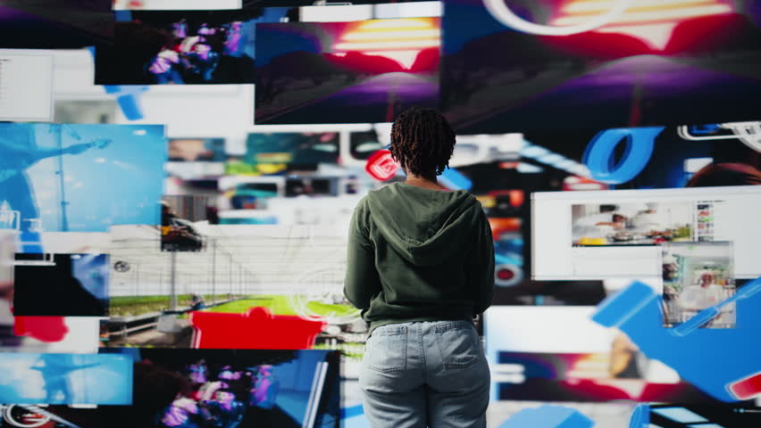 Cheerful young woman using mobile phone to browse internet, looking at surrounded by videos. Smiling african amercian teenager enjoying free time browsing online clips on smartphone, camera A