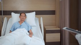 Asian doctor visiting elderly male patient resting in hospital room. Doctor asks about his condition and records medical notes on digital tablet, showing modern healthcare and patient care technology. - Powered by Shutterstock - Get 15% off with code: PIKWIZARD15
