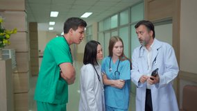 Diverse team of doctors and medical professionals from different nationalities standing in hospital corridor, discussing healthcare data and explaining information on digital tablet with teamwork. - Powered by Shutterstock - Get 15% off with code: PIKWIZARD15
