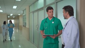 Diverse team of doctors and medical professionals from different nationalities standing in hospital corridor, discussing healthcare data and explaining information on digital tablet with teamwork. - Powered by Shutterstock - Get 15% off with code: PIKWIZARD15