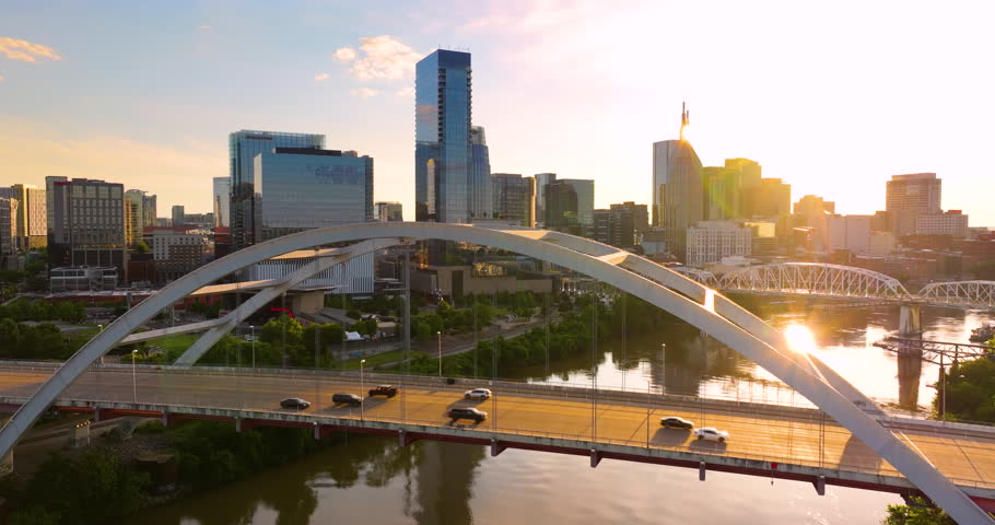 Downtown district highway bridge traffic in Nashville city, Tennessee at sunset. Brightly illuminated high skyscraper buildings in modern American midtown.