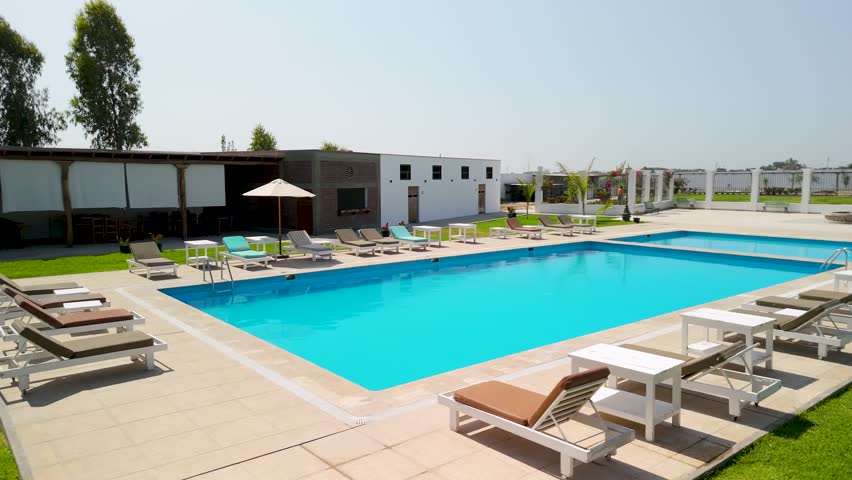 Aerial parallax shot orbiting the empty swimming pool and lounge chairs of the Bodega El Huarango a luxury hotel and winery in Ica Peru