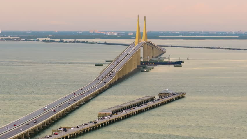Sunshine Skyway Bridge with fishing pier in Florida, USA at sunset. Driving traffic over Tampa Bay