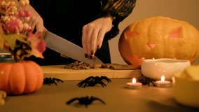 Sharp knife crushes chocolate bar into chunks on a board, table is decorated for a holiday with Halloween spiders - Powered by Shutterstock - Get 15% off with code: PIKWIZARD15