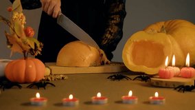 Pumpkin halves rest on cutting board as woman steadily guides knife through orange skin, soft candle flames and walnuts scattered nearby enhancing homey autumn ambiance. - Powered by Shutterstock - Get 15% off with code: PIKWIZARD15