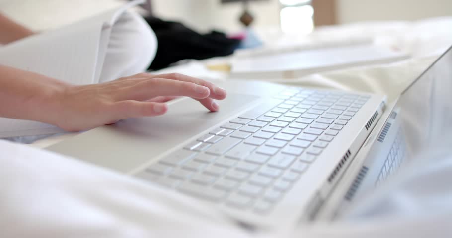 Woman's hand tapping laptop trackpad, navigating cursor sliding toward notebook for study notes. Productivity, workspace, modern, minimalist, lifestyle, comfort, technology