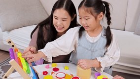 Asian mother and daughter play and learn with colorful abacus in bright, cozy living room. - Powered by Shutterstock - Get 15% off with code: PIKWIZARD15