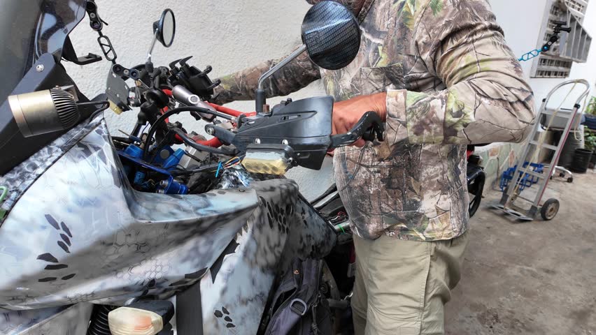 Handheld details manual work of an enthusiast checking the custom parts and controls of his personalized Off-Road Motorcycle