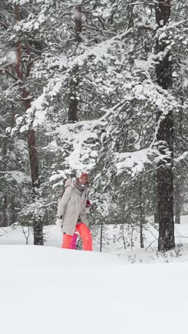 Middle-aged mother and teenage daughter enjoying walk in snowy Finland forest. Warm clothing, family values, lifestyle, togetherness and joyful winter holiday season atmosphere.