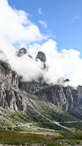 Clouds drifting across rugged mountain range in alpine vertical shot