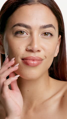 Happy woman, touch face and cosmetics in studio for results, beauty or smooth skin on white background. Person, smile and portrait with transformation, natural makeup and dermatology in Colombia