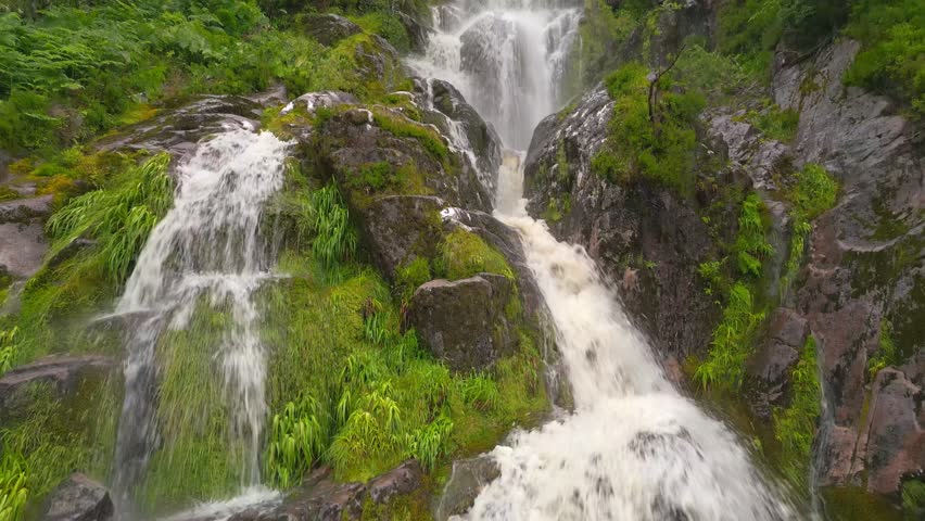 Close aerial view of a multi tier waterfall spilling over mossy rocks in the Highlands