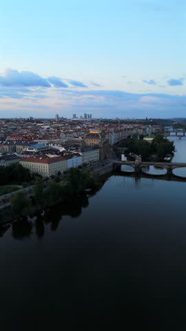 Aerial shot captures stunning historical Prague skyline and tranquil river at dusk, highlighting impressive architecture and reflections, creating a serene photography atmosphere. Czech Republic 