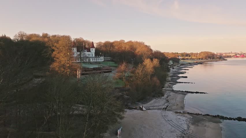Drone footage of Marselisborg Forest, the beach and Varna Mansion in late autumn near Aarhus, Denmark. Bare trees and soft coastal light capture a quiet Nordic atmosphere.