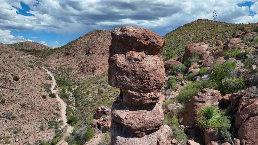 Aerial view of rock formations, a trail winds through the mountainous terrain under a cloudy sky, showcasing the rugged beauty, Globe, Arizona, United States.