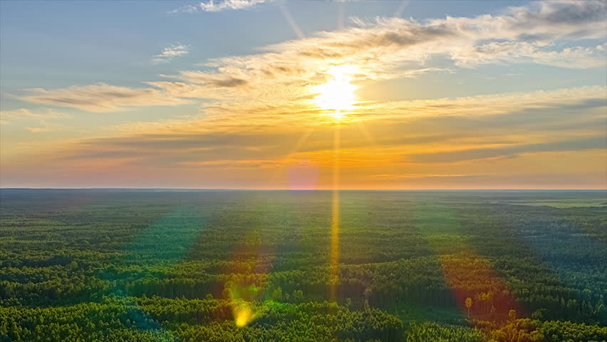 Time lapse of the sun setting over a vast forest. Aerial view