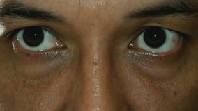 ​An extreme close-up shot of a person's dark eyes as they move and blink, staring intently into the camera. The intense focus and minimal light create a dramatic and suspenseful mood. - Powered by Shutterstock - Get 15% off with code: PIKWIZARD15