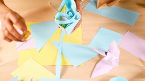 Person arranges colorful origami flowers and paper shapes under bright, even lighting, overhead view - Powered by Shutterstock - Get 15% off with code: PIKWIZARD15