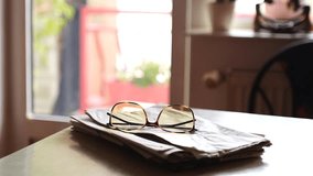 Closeup of a man's hands taking glasses from a pile of newspapers on a kitchen table to read them - Powered by Shutterstock - Get 15% off with code: PIKWIZARD15