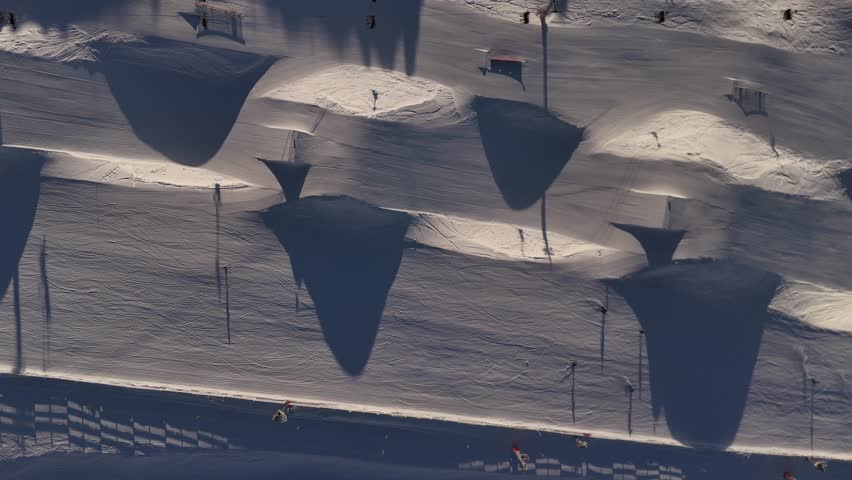 Aerial top down view of skiers, enjoying skiing and winter sports at Cardrona Ski Resort in New Zealand surrounded by stunning snow-covered mountains.