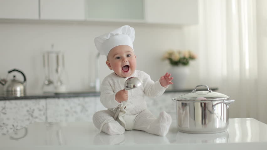 Happy little chef with a ladle knocking on a pan and laughing

