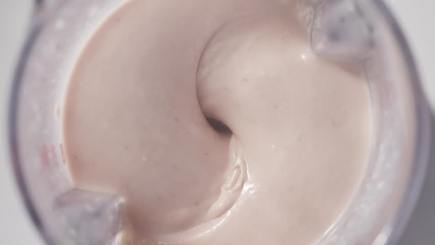 Strawberry and banana pink milkshake blended in blender with splashes. top view. slow motion. Healthy protein smoothie drink concept , food closeup