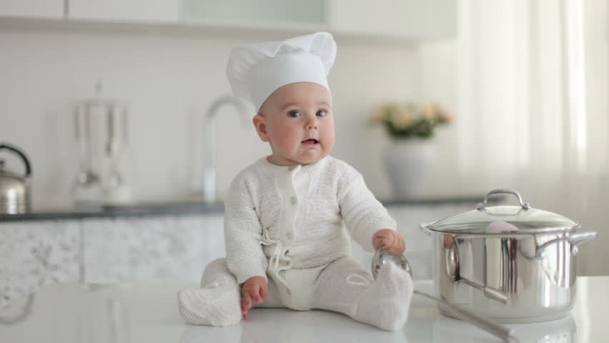 Baby boy with a ladle sitting on table. Little chef. 
