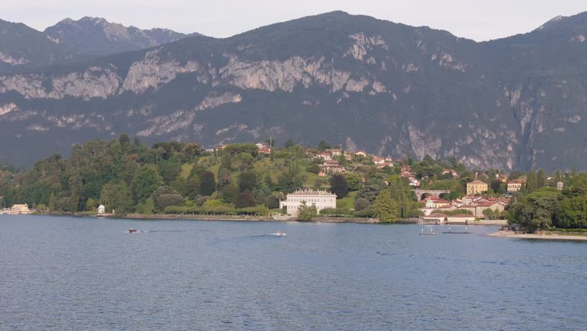 A 4K aerial over Villa Melzi, Lake Como lakeside villa with mountains rising behind , cinematic panoramic establishing shot.