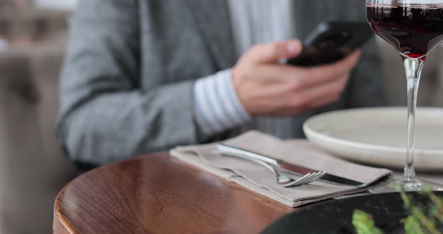 Close up man paying restaurant bill using credit card. Couple spending date in restaurant. Waiter giving terminal wifi scan using smartphone contactless NFC payment.