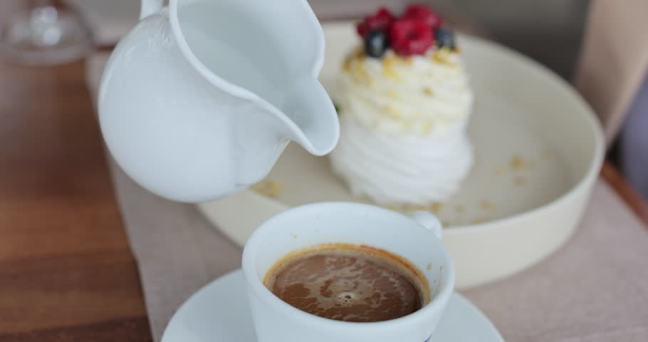 Hot cream is poured into coffee. Coffee with froth close up.
