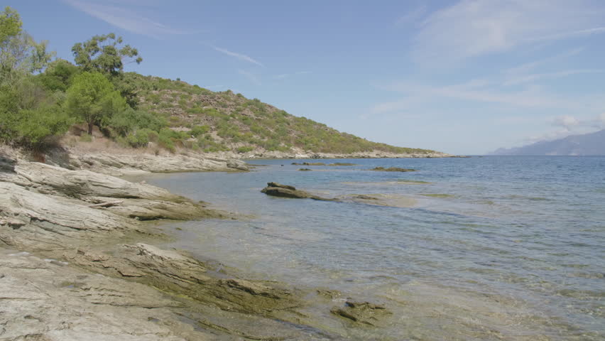 Saint-Florent Corsica coast sunny view of crystal clear turquoise water, rocky shorelines under a bright blue sky serene Mediterranean landscape untouched natural beauty northern Corsican seaside