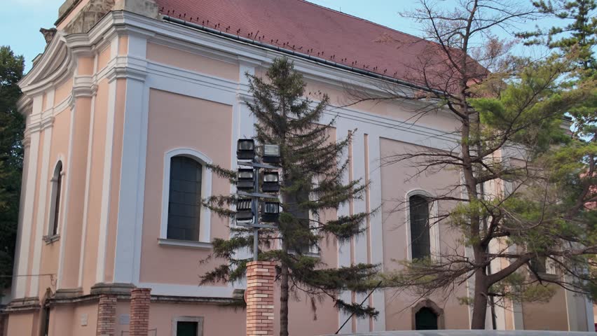 Tilt-up shot of Szeged’s Church of St. Nicholas, showcasing its tower and historic architecture.
