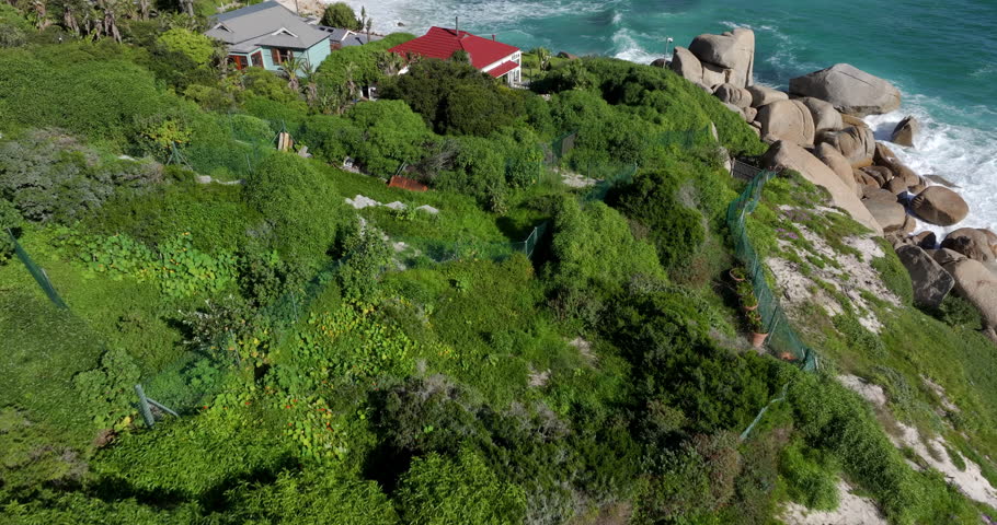 Aerial tilt up shot of Camps Bay beach on a sunny day in Cape Town, Western Cape, South Africa. 