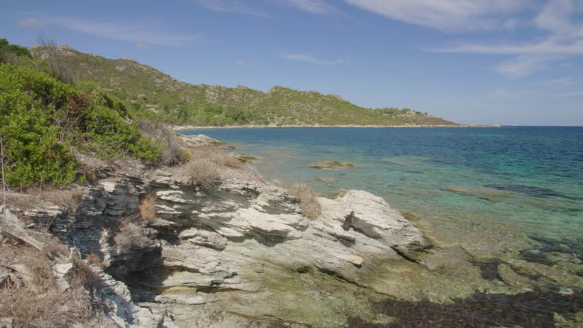 Saint-Florent Corsica coast sunny view of crystal clear turquoise waters, rocky shorelines under a bright blue sky untouched natural beauty northern Corsican seaside serene Mediterranean landscape