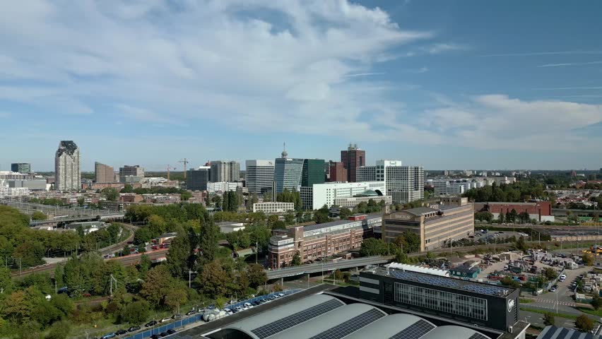 An aerial view of the Dutch Hague city with high-rise buildings, trees, industrial zone and multiple train railways at the daytime in Netherlands