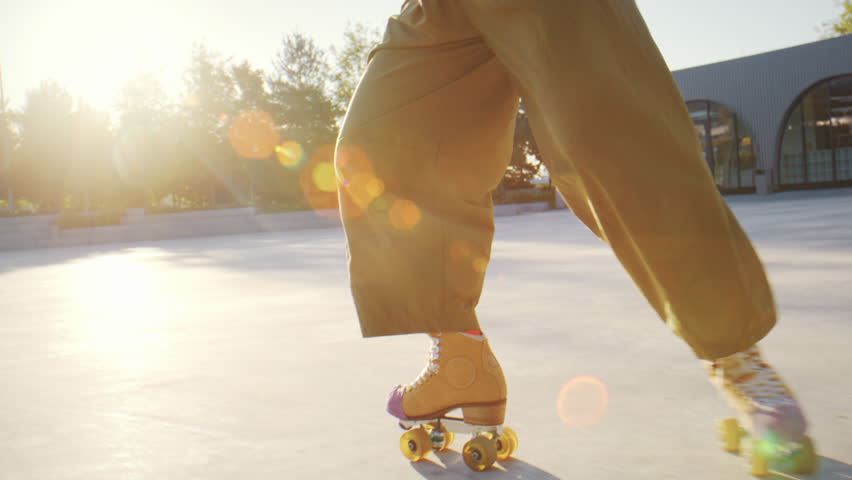 Sportive woman wearing old fashioned quad skates trains on sports ground slow motion. Skilled female skater slides and turns around on street closeup