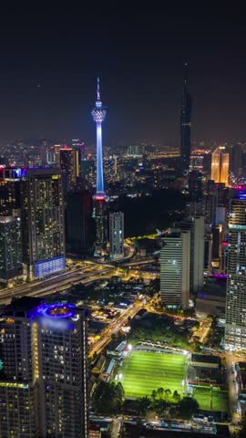 Aerial timelapse of Kuala Lumpur city at night with bright lights, traffic trails, and modern skyscrapers creating vibrant urban skyline in Malaysia.