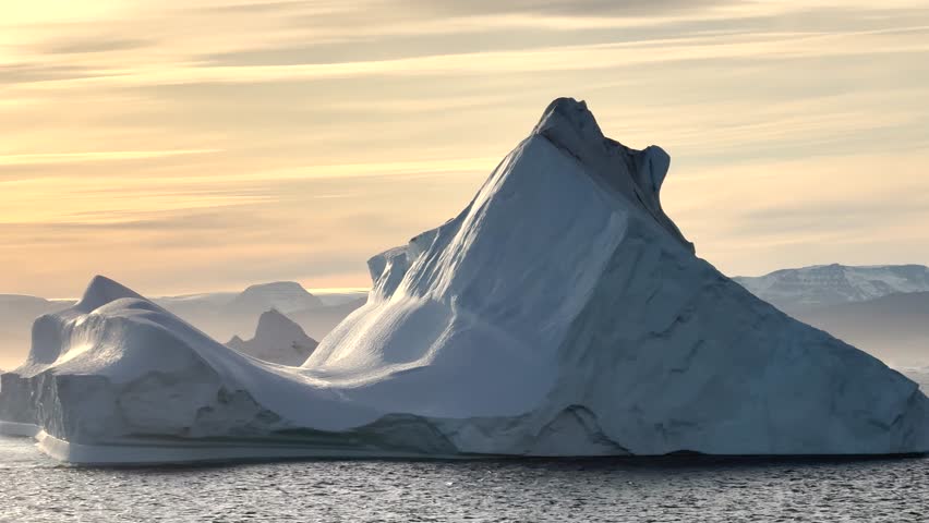Experience the breathtaking coastal beauty of Baffin Island, where glistening icebergs meet serene waters against a backdrop of mountains at dawn.
