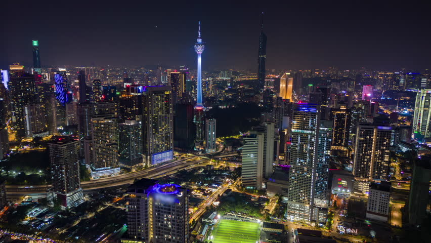 Aerial timelapse of Kuala Lumpur city at night with bright lights, traffic trails, and modern skyscrapers creating vibrant urban skyline in Malaysia.