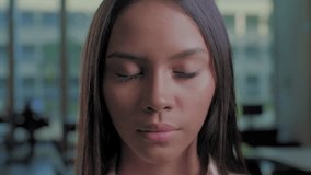 Close-up of a young woman with eyes closed, slowly opening them to look directly at the camera. Calm and introspective moment in a modern indoor setting, symbolizing focus, awareness, and self-reflect - Powered by Shutterstock - Get 15% off with code: PIKWIZARD15