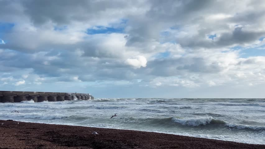 Stormy shoreline near Brighton with dramatic waves under cloudy sky