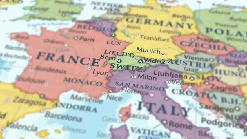 4K macro video of Switzerland on a world map with shallow depth of field. Focus on word Switzerland and surrounding areas including France, Germany, Italy, and Austria. Travel geography footage