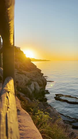 Sunrise over the sea in Rincón de la Victoria, Malaga, Spain, with golden light reflecting on calm waves along the coast.