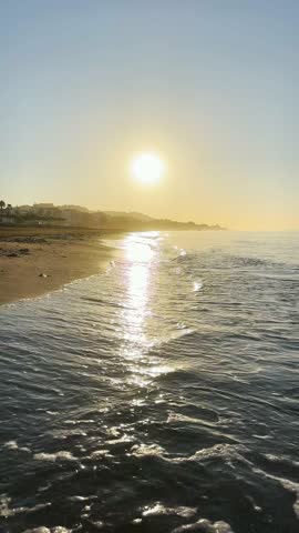 Sunrise over the sea in Rincón de la Victoria, Malaga, Spain, with golden light reflecting on calm waves along the coast.