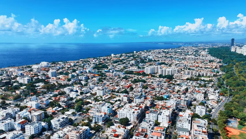 Panoramic daytime cityscape of Santo Domingo, Dominican Republic, with modern high-rise buildings. Amazing summer view of the Caribbean coast. The blue ocean meets the clear sky on the horizon.