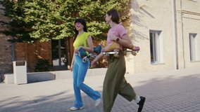 Young women stroll along quiet street with quad skates resting on shoulders. Friends swing arms in light rhythm enjoying small talk while cheerful mood builds - Powered by Shutterstock - Get 15% off with code: PIKWIZARD15