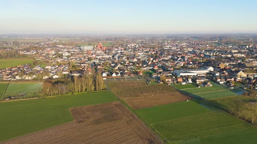 village merchtem belgium train tracks empty green fields snow covered areas perspective old homes roads markets against distant horizon reveals long view