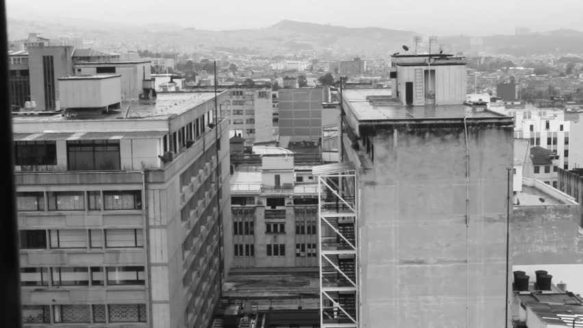 Fixed black and white shot of the rooftops and facades of buildings in a city, with hills and more city in the background.
Bogotá, Colombia.
Taken on April 4, 2022