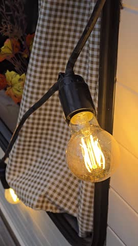 Cozy autumn evening scene with warm string lights, checkered curtain, and fall harvest decor by a trailer window, creating a festive, rustic atmosphere. autumn season,  autumn concept, fall