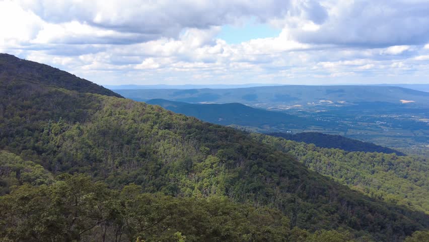A scenic overlook reveals layers of rolling hills and a distant valley under a clear blue sky near Shenandoah National Park, Virginia, U.S.A